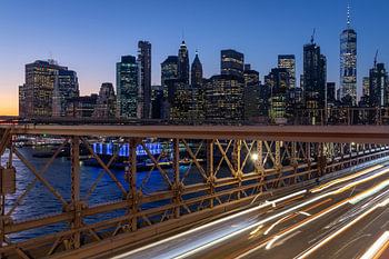 New York skyline from Brooklyn Bridge at night long exposure shot with light trails from moving cars
