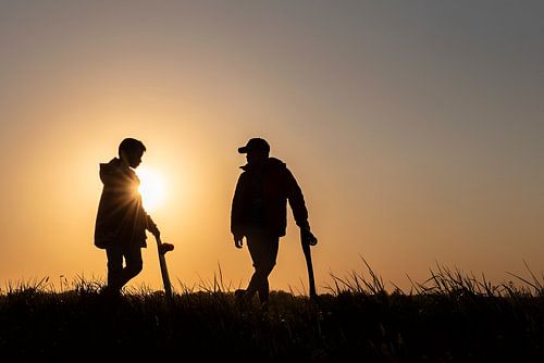 Twee jongens met skateboard bij zonsondergang