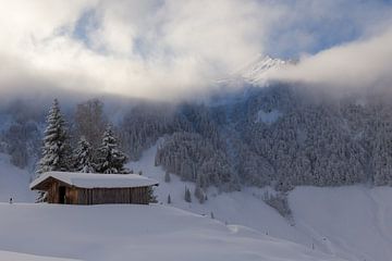 Berghütte im Schnee mit aufziehenden Wolken