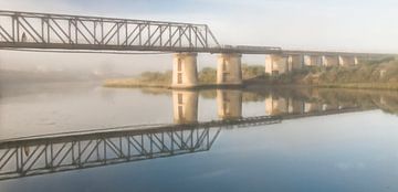 Radfahrer auf Eisenbahnbrücke im Abendlicht  von Marcel van Balken