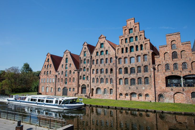 Warehouses with tour boat in old town Lübeck, Germany by Joost Adriaanse