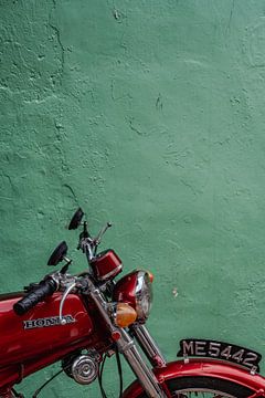Koele groene muur in Malakka met een mooie contrasterende rode motorfiets. van Marcus PoD