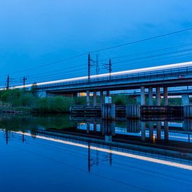Streaks of light from a train on a railway bridge at dusk by Eugene Winthagen