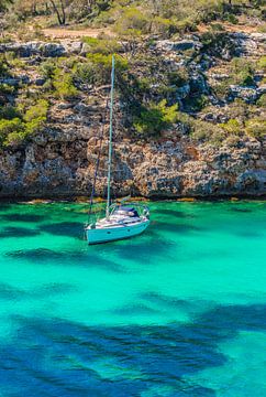 Idyllic bay with anchored sailing yacht at beautiful sea coast by Alex Winter