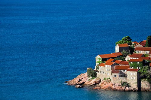 Cute fishing village. small houses with a tiled roof and green trees by the blue sea. happiness in r
