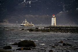 A fishing boat sails past the Høgstein lighthouse on Godøy, Norway by qtx
