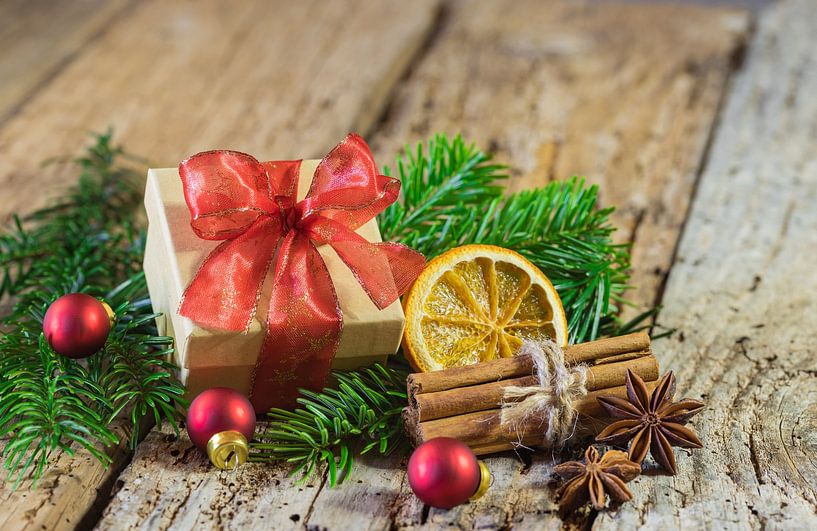 Christmas gift box with red ribbon and decoration on wooden table by Alex Winter
