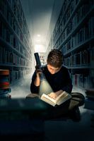 Boy reading in the dark in a library,