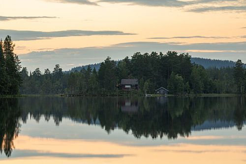 Typisch Zweedse stuga tussen de bomen aan het meer