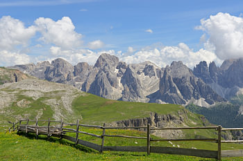 The Rosengarten Mountains, with green pastures and a wooden fence