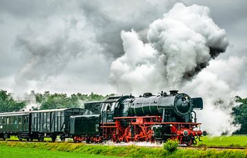 Stoomtrein op het platteland met dikke rookwolken uit locomotief