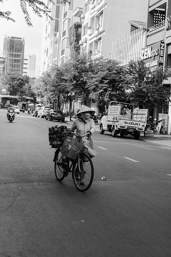 Frau mit Fahrrad geht auf der Straße in HCMC