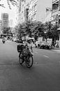 Vrouw met fiets loopt over straat in HCMC van Bart van Lier thumbnail