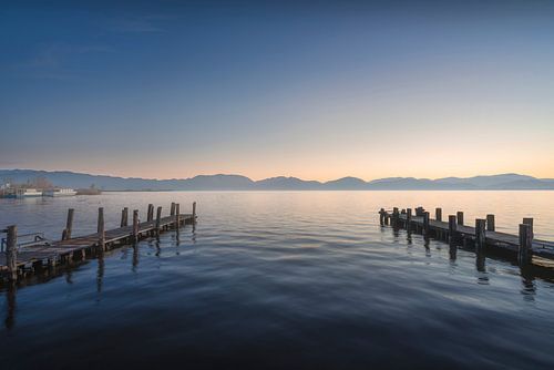 Twee houten pieren bij zonsopgang in het Massaciuccoli meer