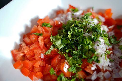Tomaten, ui, basilicum in een kom.
