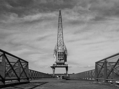 Industriële hijskraan met dramatische lucht in zwart-wit