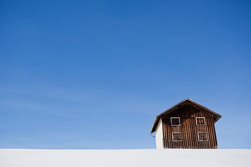 Alleen in het wit – houten hut in de sneeuw