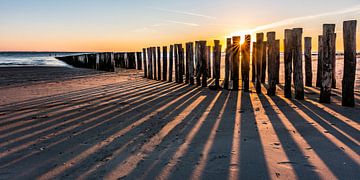 Coucher de soleil entre les brise-lames de la plage de Dishoek sur Jan Poppe