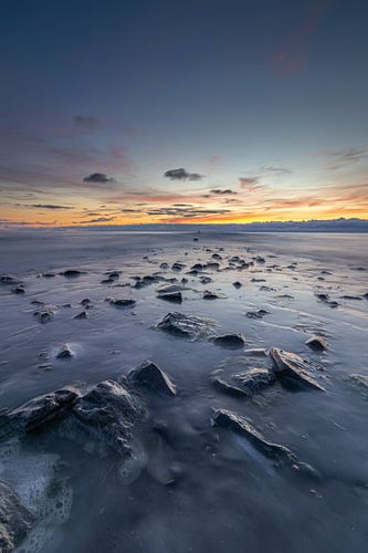 De pier komt langzaam tevoorschijn wanneer de zee zicht terugtrekt tijdens een kleurrijke zonsondergang