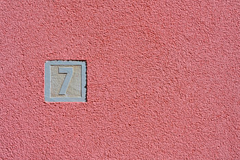 House number seven against a pink wall