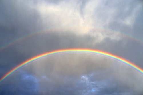 A double rainbow over a lake before a thunderstorm