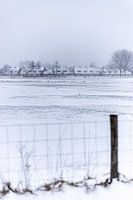 Een Nederlands dorp in de sneeuw achter een hek