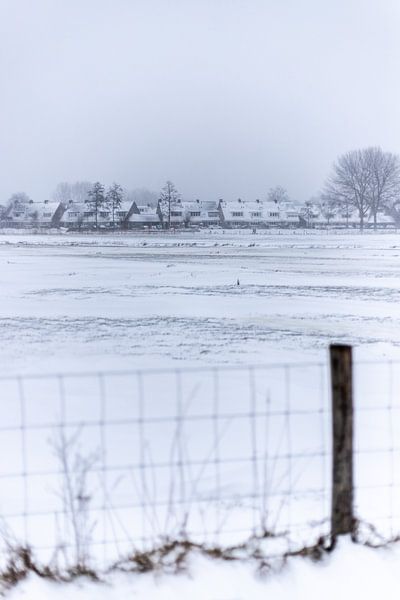 Een Nederlands dorp in de sneeuw achter een hek van Thomas Winters