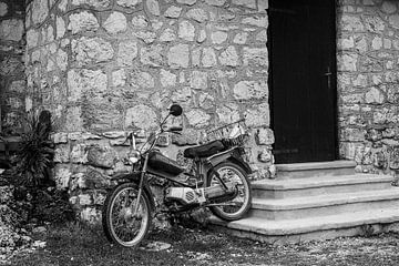 Oude motorfiets voor huismuur