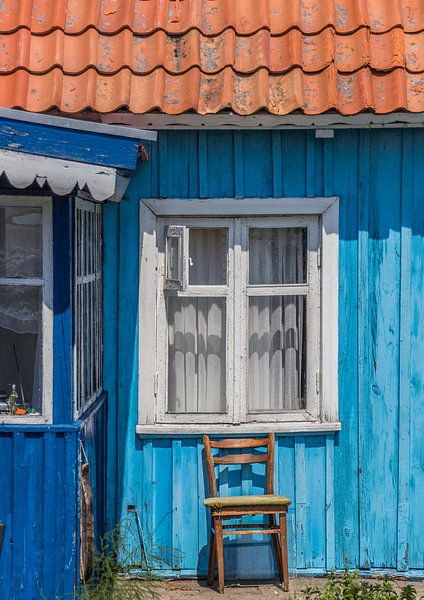 Chair in front of a blue wooden house in Nida by Marc Venema