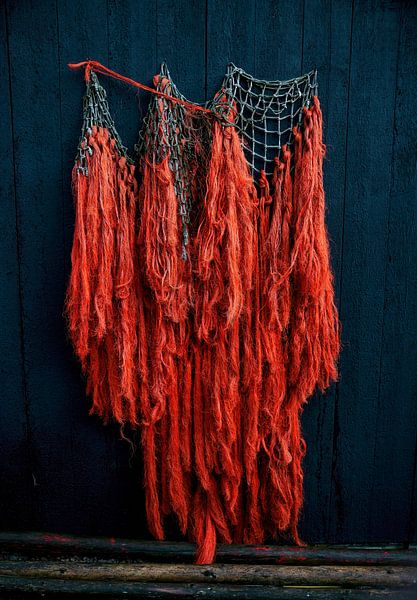 Orangefarbene Fischernetze hängen auf einem dunkelblauen Holzhintergrund im Museum auf Texel von ChrisWillemsen