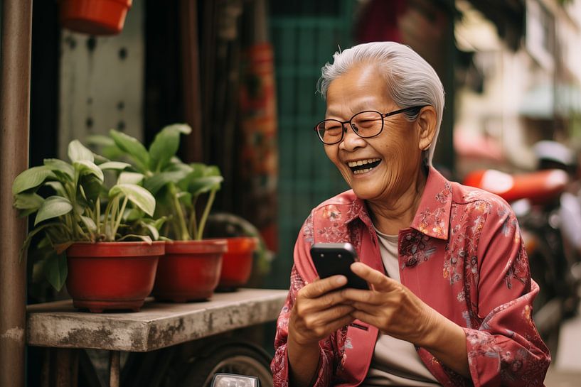 Une femme âgée d'Asie du Sud-Est sourit avec son téléphone sur un marché asiatique par Animaflora PicsStock