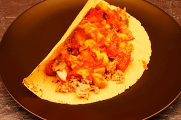 Gefüllter Tacos mit Hackfleisch, Avocado, Tomate und Salat auf schwarzem Teller