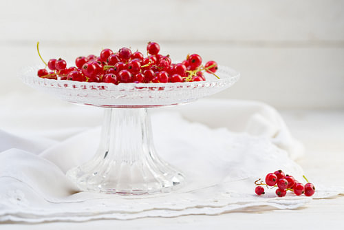 rote Johannisbeeren in einer eleganten Glasschale auf einem weißen Tischtuch, Kopierraum, ausgewählt