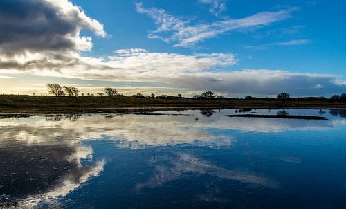 Spiegeling van de lucht in een bevroren ven
