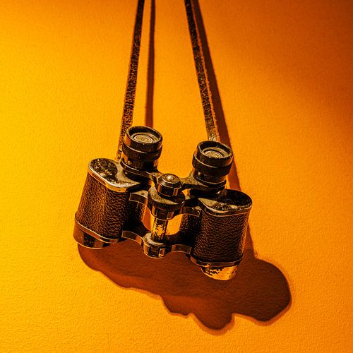 Vintage‑Fernglas am Lederriemen – warmer Orangeton | minimalistisches Industrial‑Stillleben