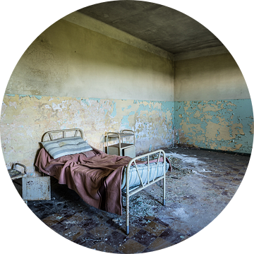 Bed met nachtkastje in een verlaten zorginstelling