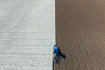 Tractor ploegt de grond voor het planten van gewassen van bovenaf gezien