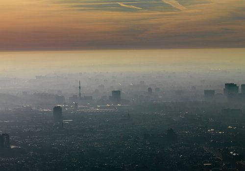 Tegenlichtopname van het centrum van Amsterdam waarbij een nevel over de stad ligt.