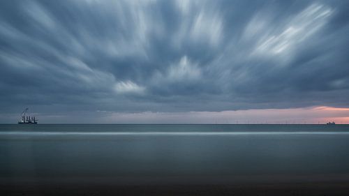 Paysage marin au coucher du soleil avec des nuages menaçants.