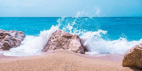 De witte golven breken op een rots op het strand
