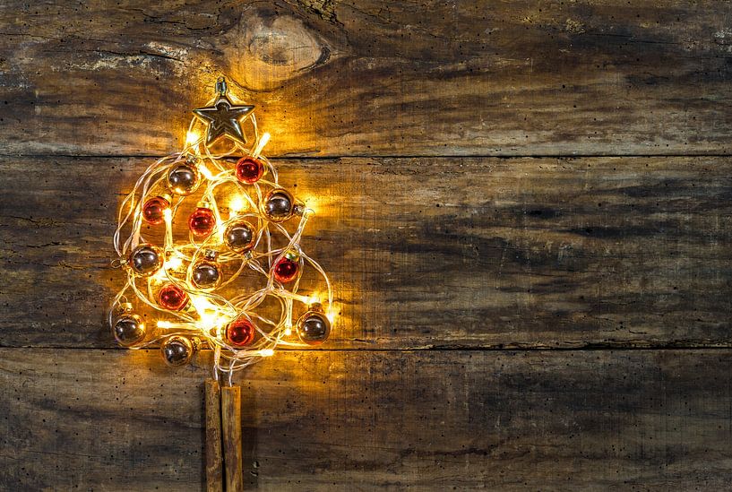 De vorm van de kerstboom met versieringen en warm licht op houten achtergrond van Alex Winter