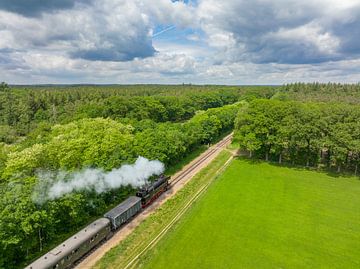 Steam train with smoke from the locomotive driving through the c by Sjoerd van der Wal