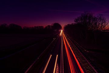 Beautiful glow in the sky with light trails on the road by Rob Baken
