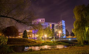 Photographie nocturne colorée du parc de la ville d'Eindhoven avec un bâtiment sur Loes van Dijk