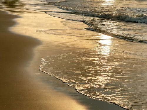 Fotografie: Goldenes Sonnenlicht auf den Wellen am Strand
