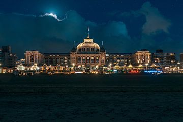 Kurhaus Scheveningen tijdens blauwe uurtje waarbij de maan door de wolken langzaam tevoorschijn komt van Jolanda Aalbers