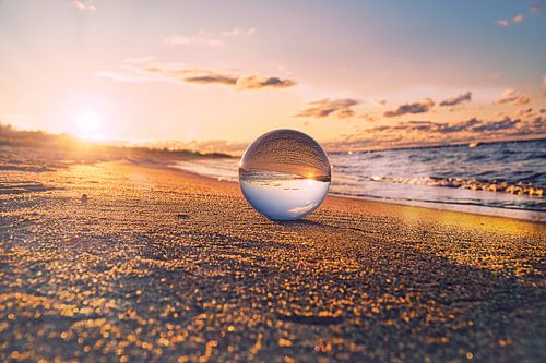 Sphère de verre sur la plage de Zingst, au coucher du soleil. Le soleil et la mer Baltique se reflèt