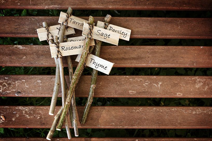 kreative Pflanzenmarker auf einem Holztisch, beschriftet mit Kräuternamen für den ländlichen Garten, von Maren Winter