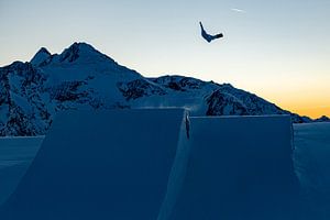 Snowboarder vliegt hoog boven de alpentoppen van Hidde Hageman