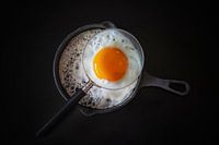 Still life with fried egg with magnifying glass